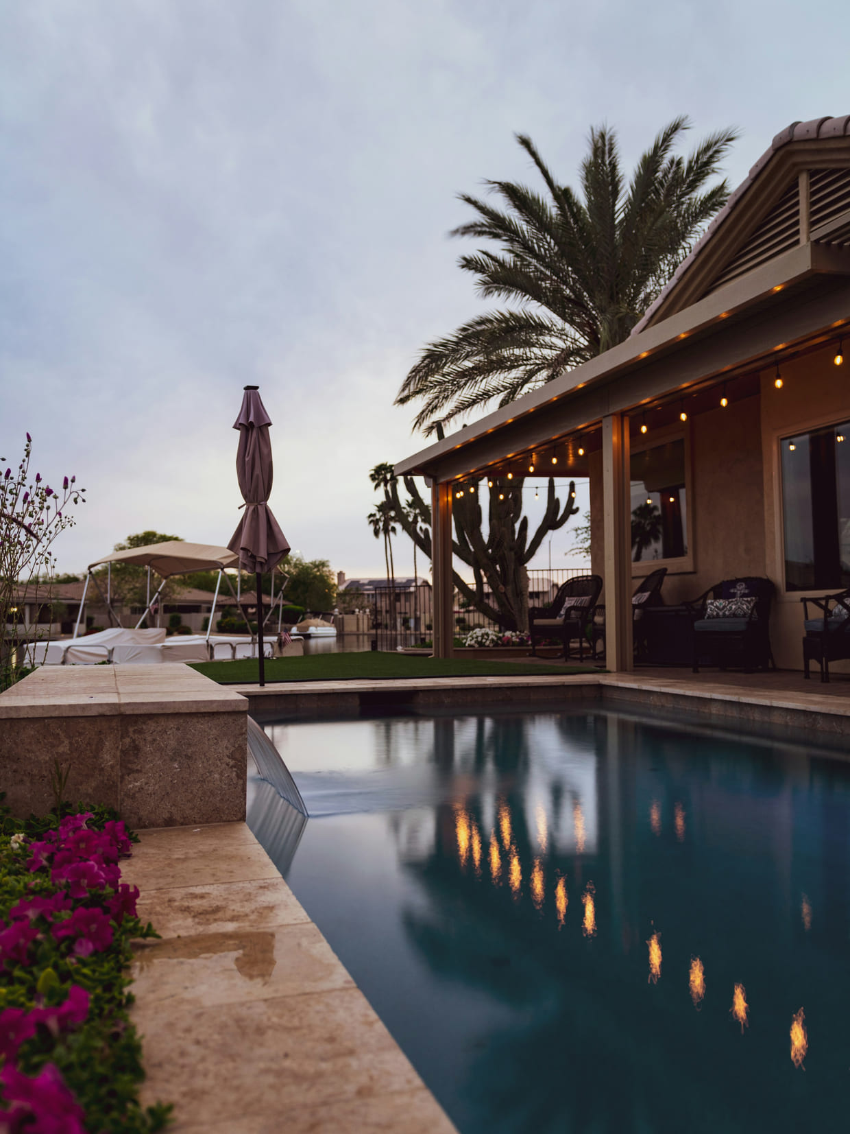 Terraza cubierta de una villa con palmeras y piscina al atardecer