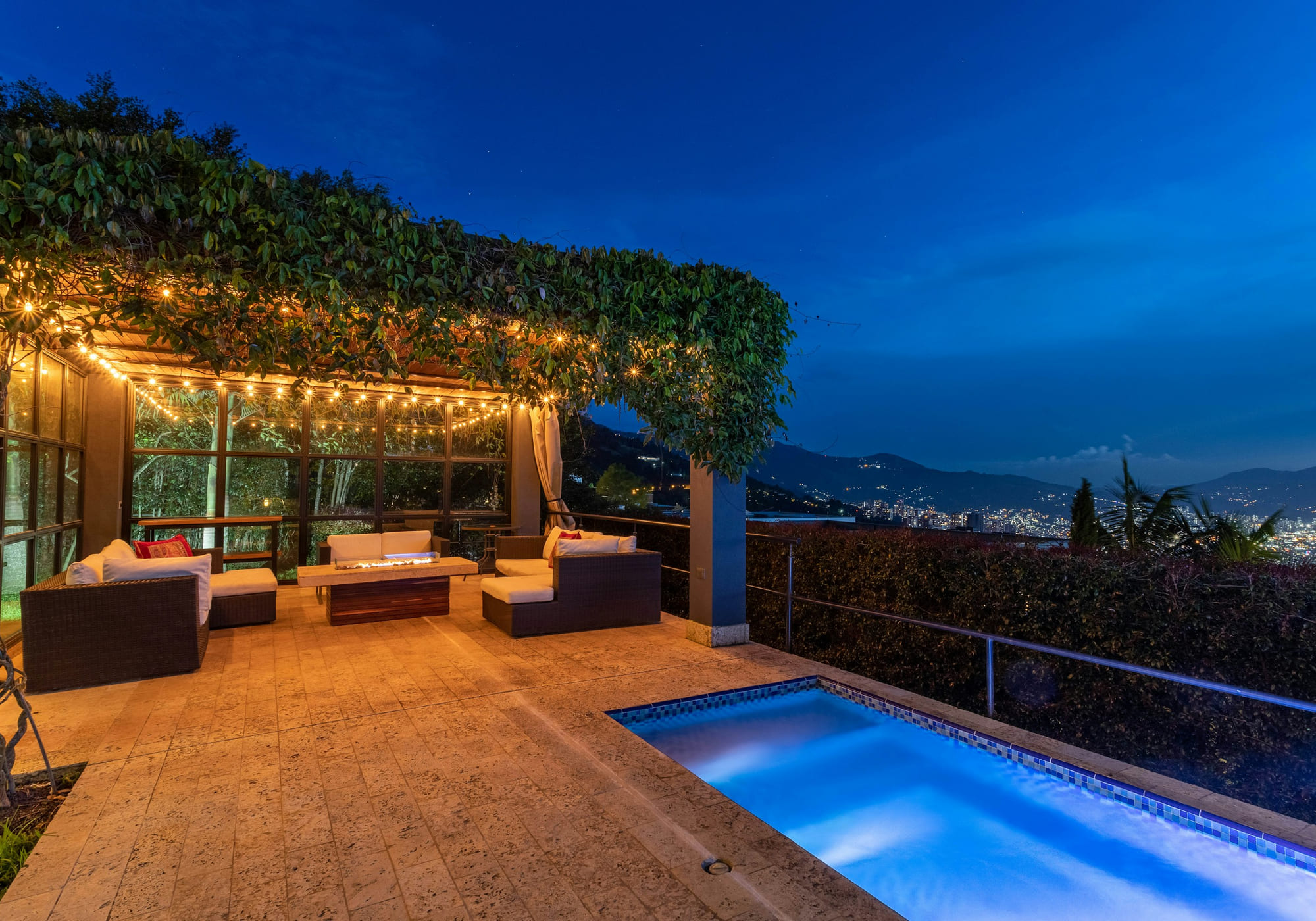Pérgola iluminada junto a la piscina de una villa privada al anochecer