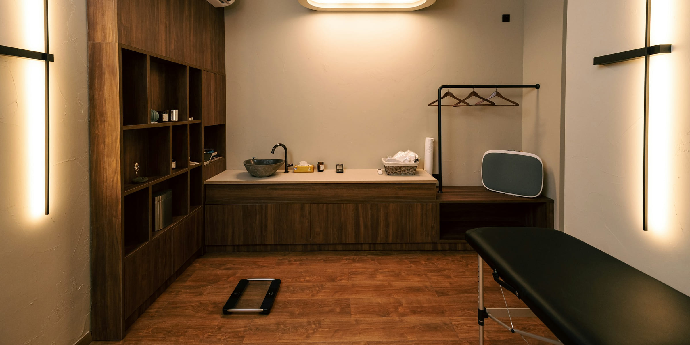 Sala de recuperación con camilla, madera cálida y luz suave, sin personas